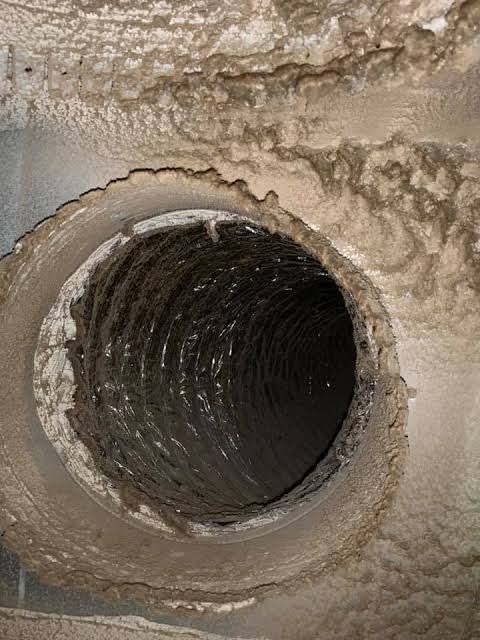 Heavy dust and debris caked inside an HVAC duct in a Raleigh, NC home